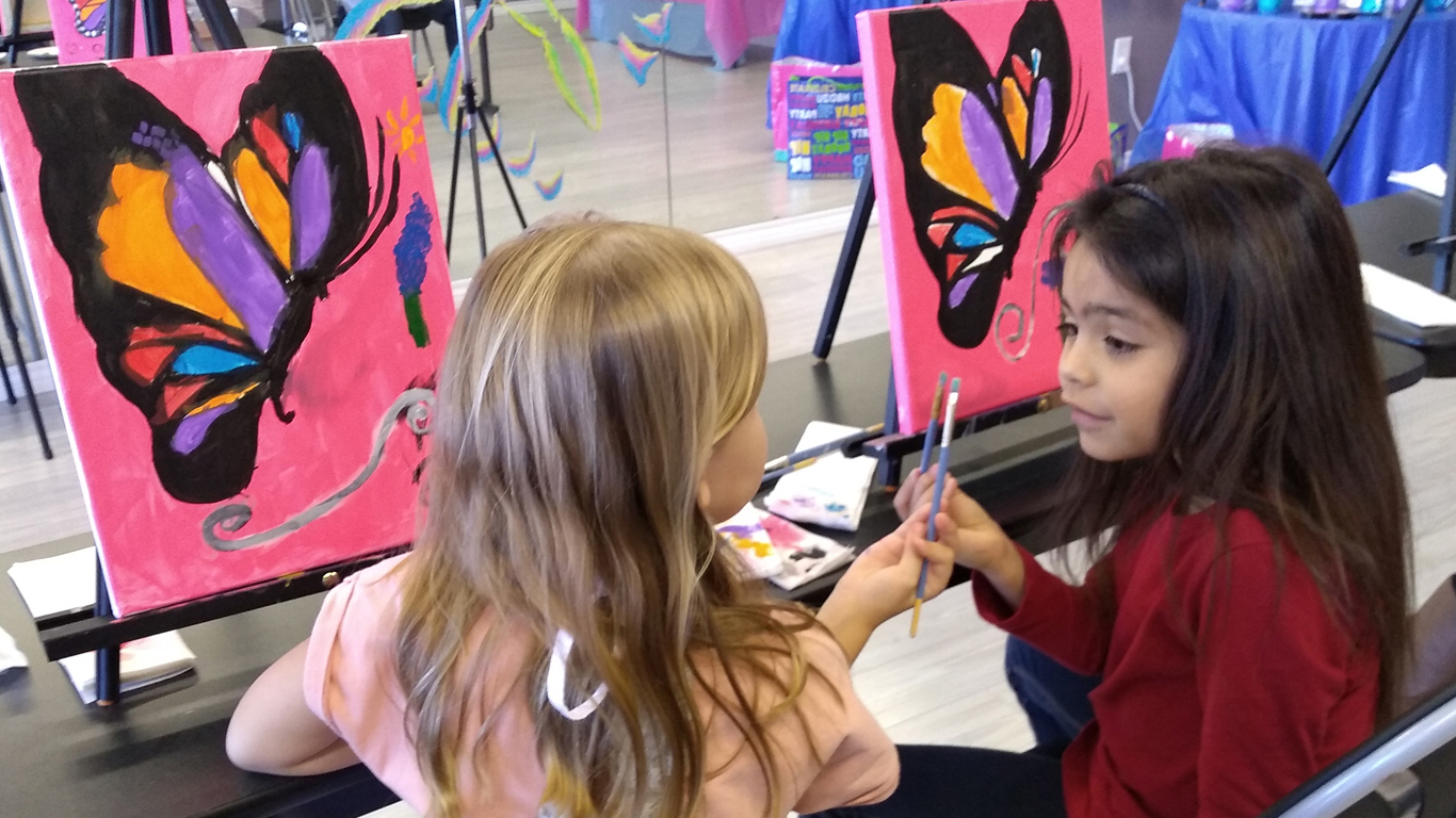 two children touch paint brushes